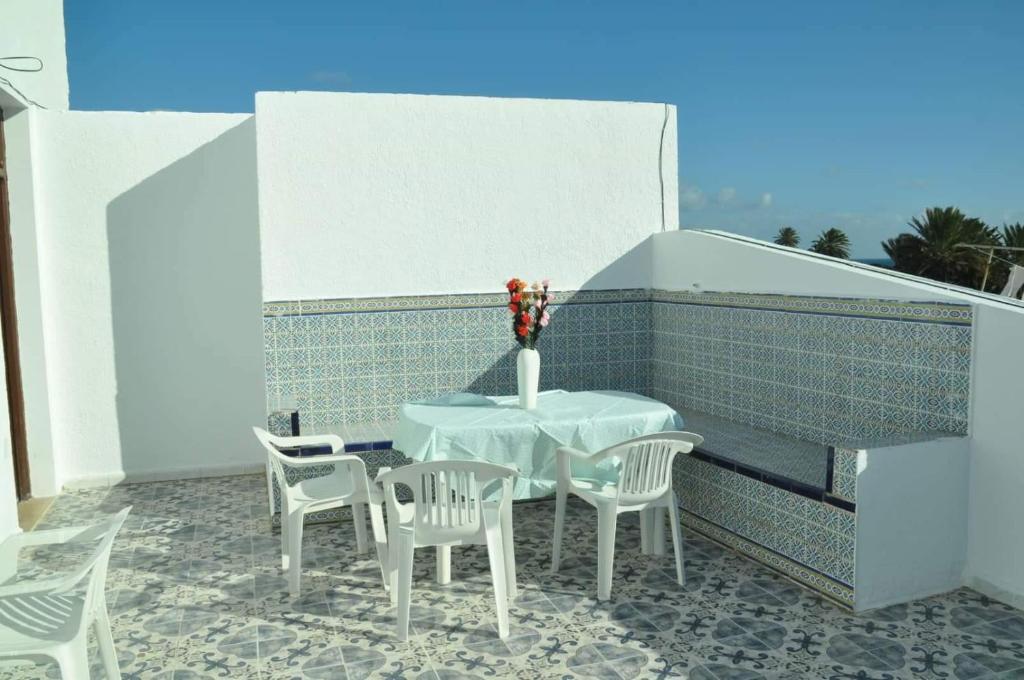 马赫迪耶City Apartment sur le port de Mahdia Free Wifi的一张白色的桌子和椅子,阳台上有一个花瓶