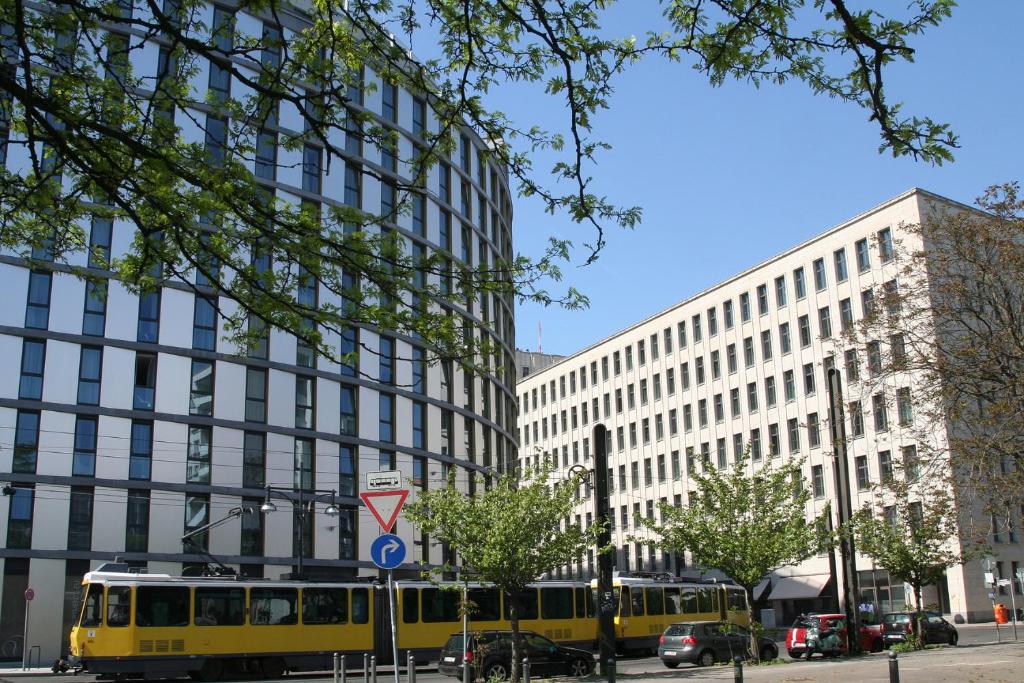 柏林亚历山大广场假日公寓酒店的一条黄色的公共汽车在城市街道上,有建筑