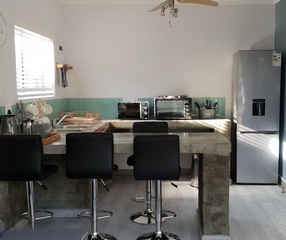 布隆方丹Emmaus Apartment的厨房配有桌椅和冰箱。