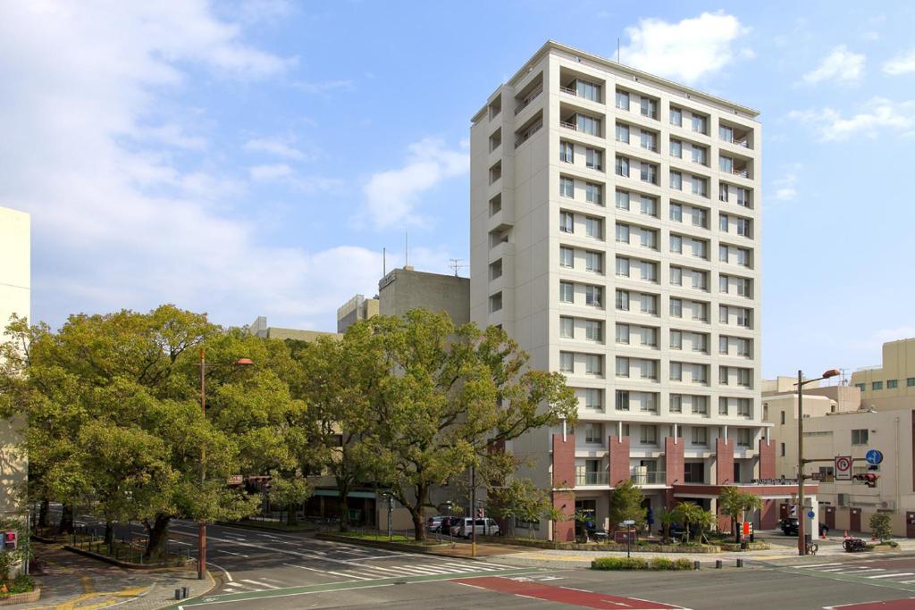 宫崎K's Street Hotel Miyazaki的一条树木繁茂的城市街道上高大的白色建筑