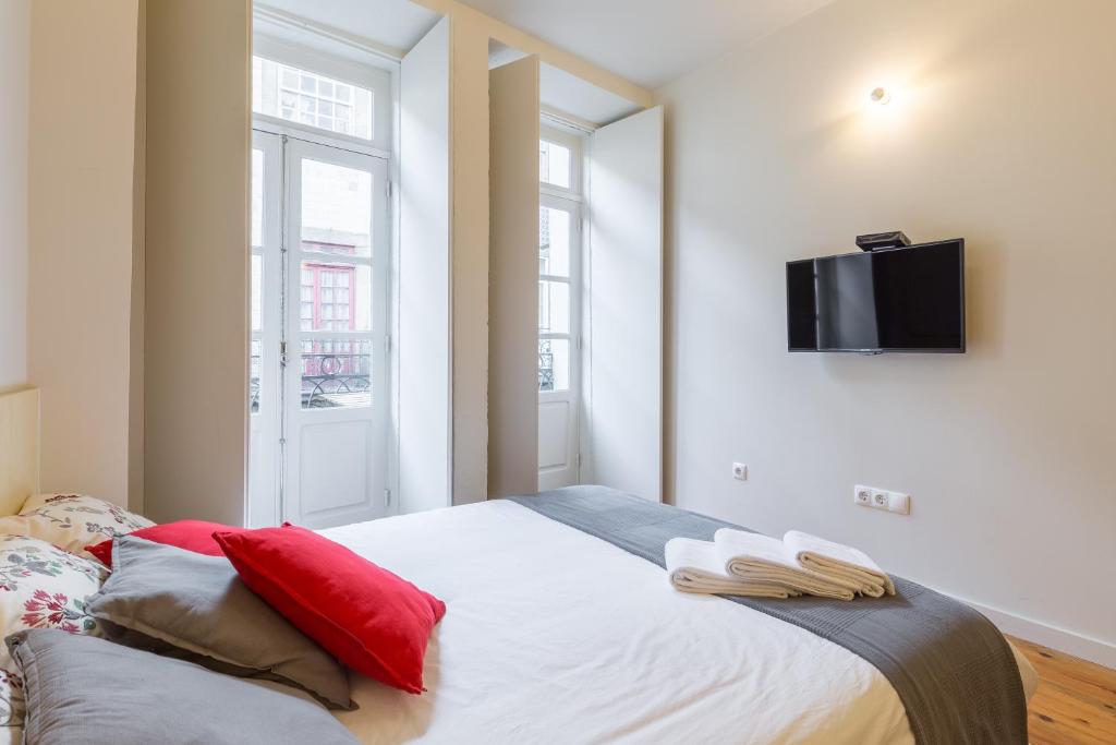 波尔图House in Porto Historical Center T1的一间卧室配有一张带红色枕头的床和一台墙上的电视。