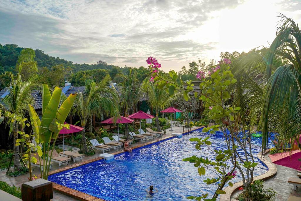 富国Phu Quoc Bambusa Resort的度假村的游泳池,配有椅子和遮阳伞
