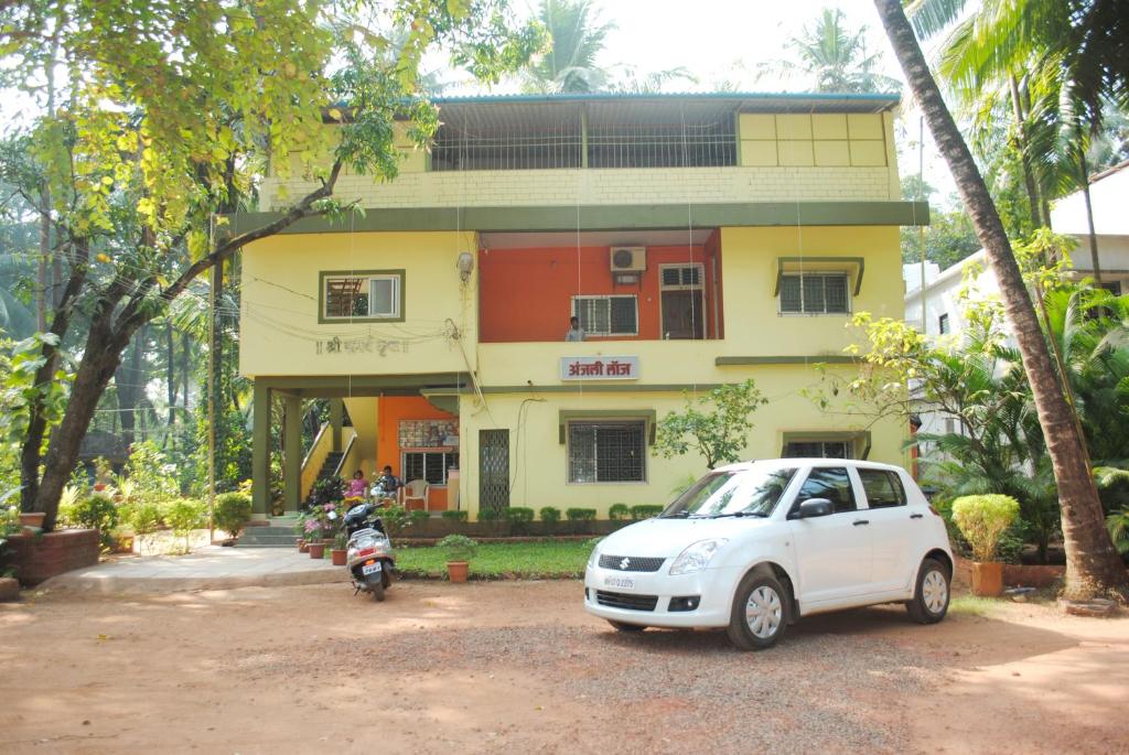 马尔万Hotel Anjali Lodge Malvan的停在大楼前的白色汽车