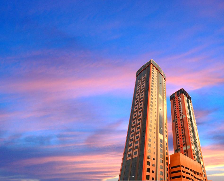 麦纳麦Orange Suites Hotel的日落时分在城市里两座高耸的摩天大楼