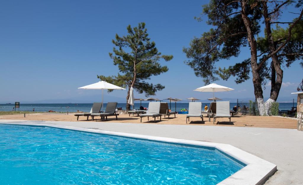 斯卡拉拉乔伊Rachoni Imperial的海滩旁的游泳池,配有椅子和遮阳伞