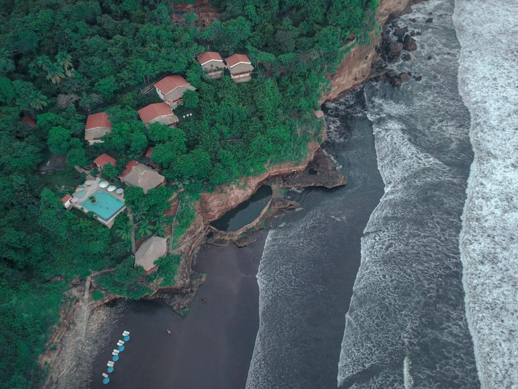 El NísperoParaiso Escondido Hotel Villas & Resort的靠近大海悬崖上房屋的空中景观