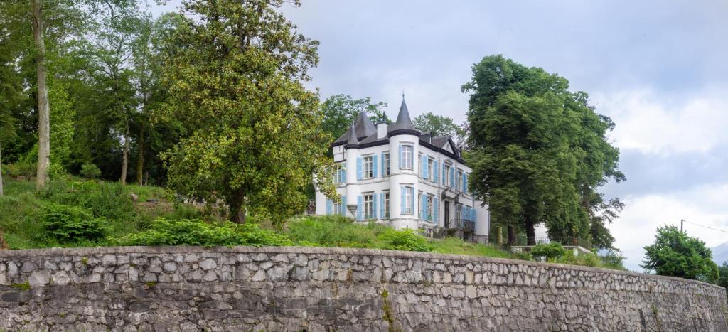 Sévignacq-MeyracqChâteau de Druon的一座白色的大房子,位于一座小山上,设有石墙