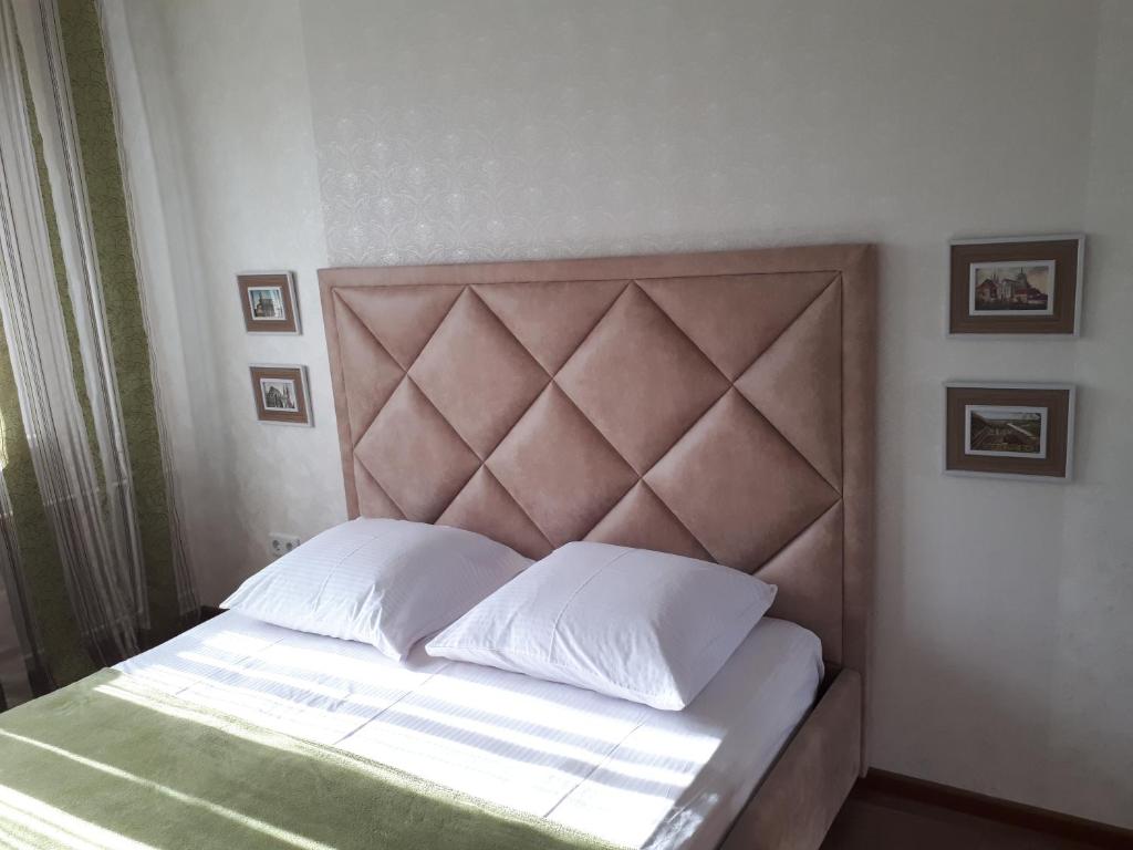 日托米尔Nebesnoyi Sotni的一张带白色枕头和棕色床头板的床