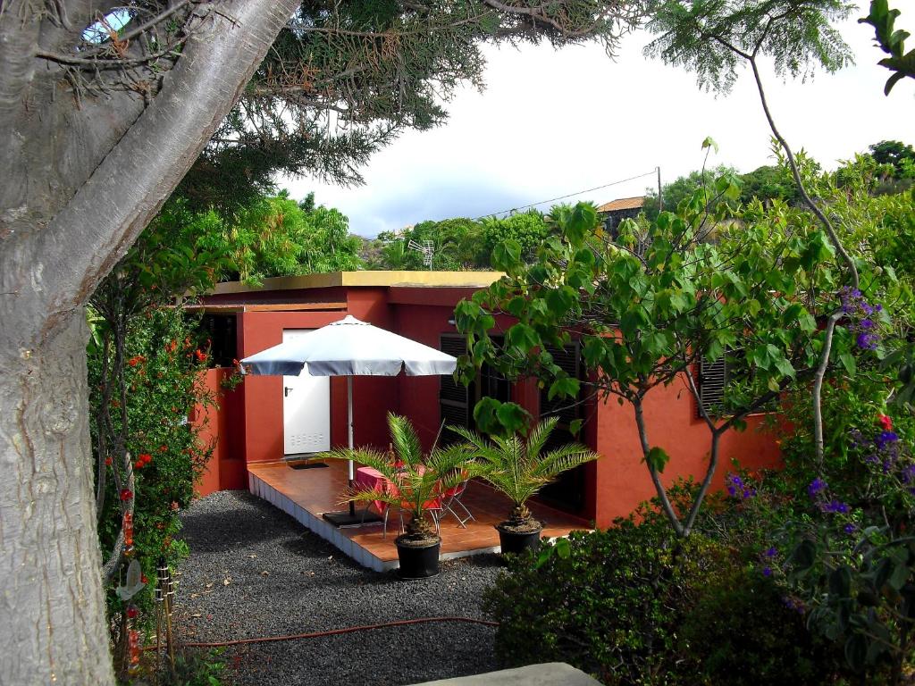 洛斯·亚诺斯·德·阿里丹Casa Sandra en Las Norias Todoque con Wi-Fi的一座红色的房子,上面有白色的伞和一些植物