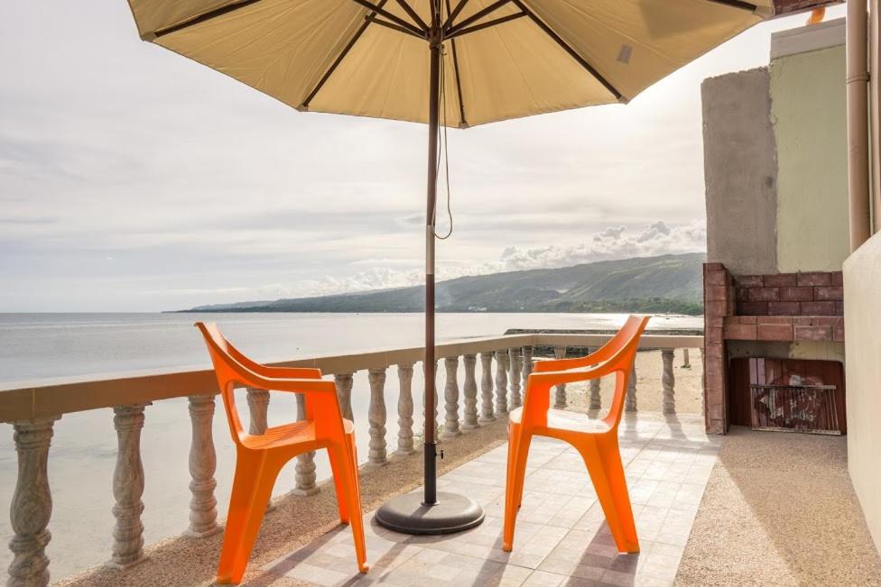 达拉盖地Kellocks' Seaview Apartelle的阳台上配有两把橙色椅子和一把遮阳伞