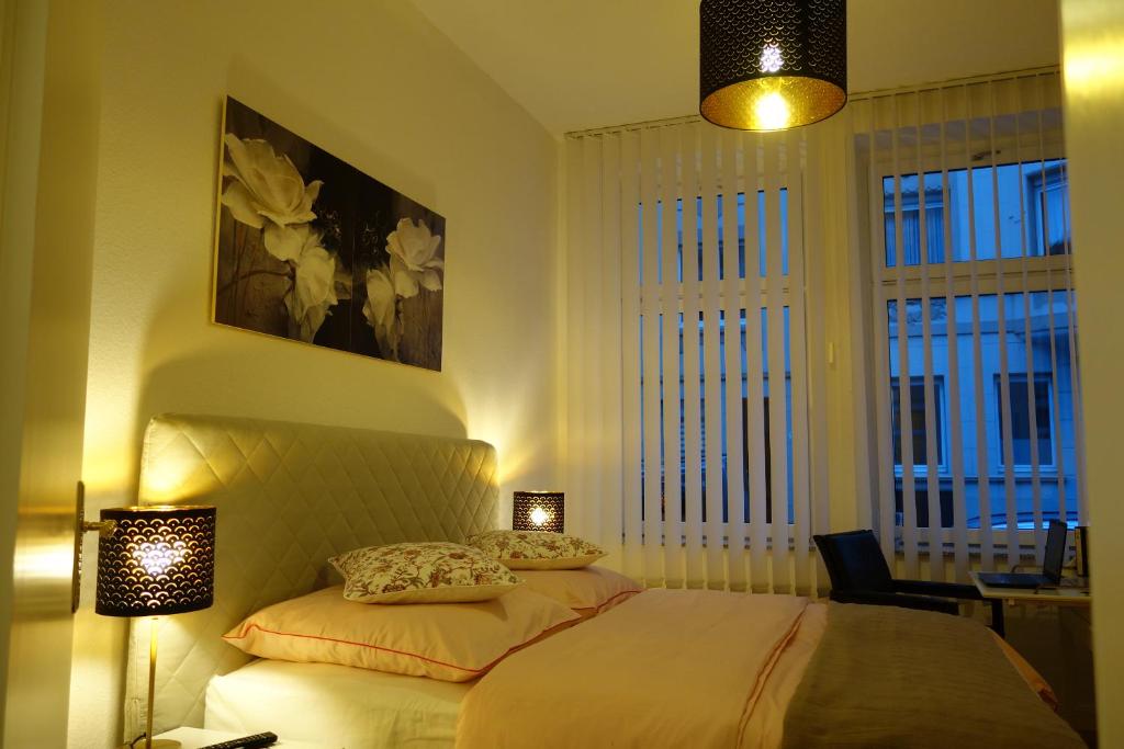 伍珀塔尔Nettes, gemütliches Apartment的一间卧室配有一张带两个灯和两个窗户的床
