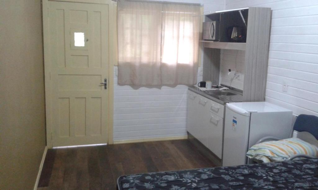 格拉玛多Chalé da Tranquilidade的一间小厨房,配有白色的门和水槽
