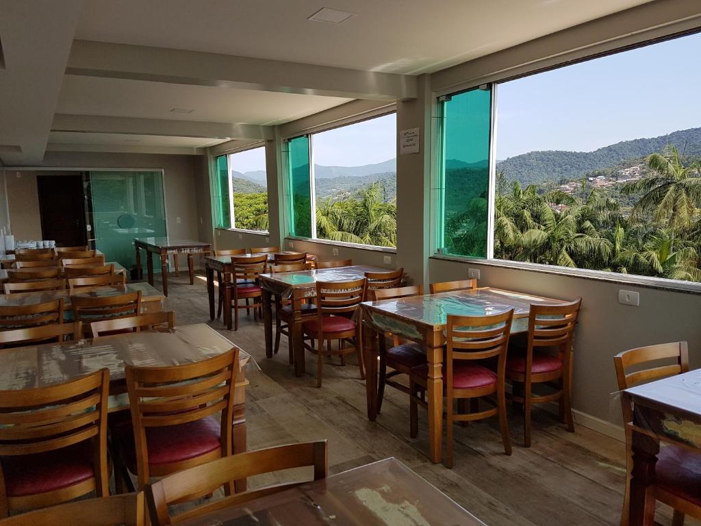 布卢梅瑙Pousada Do Galdino的餐厅设有桌椅和大窗户。