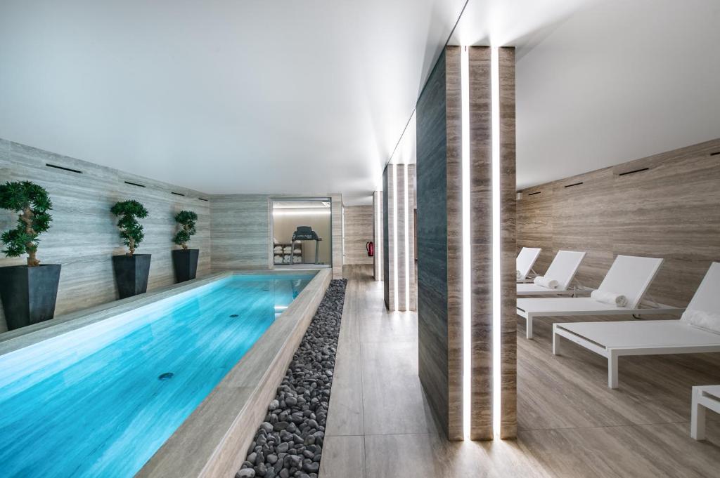 日内瓦帕契斯9酒店的一座配有白色家具的无边游泳池
