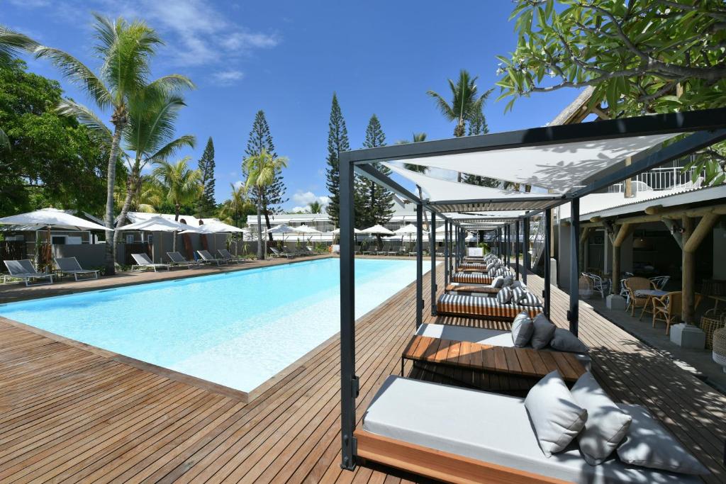塔马兰沃兰达塔玛林Spa酒店的毗邻度假酒店的带椅子和遮阳伞的游泳池