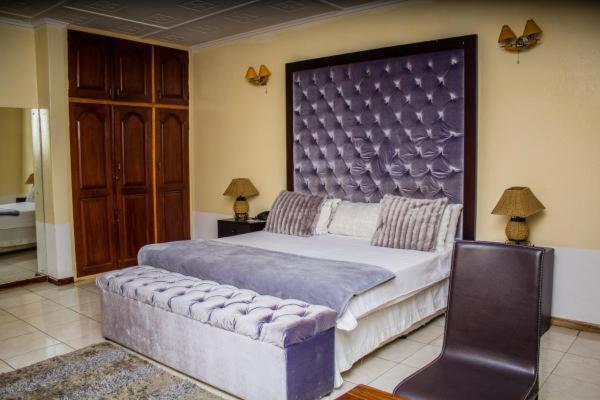 卢萨卡Rugems Executive Lodge的一间卧室配有一张大床和大床头板