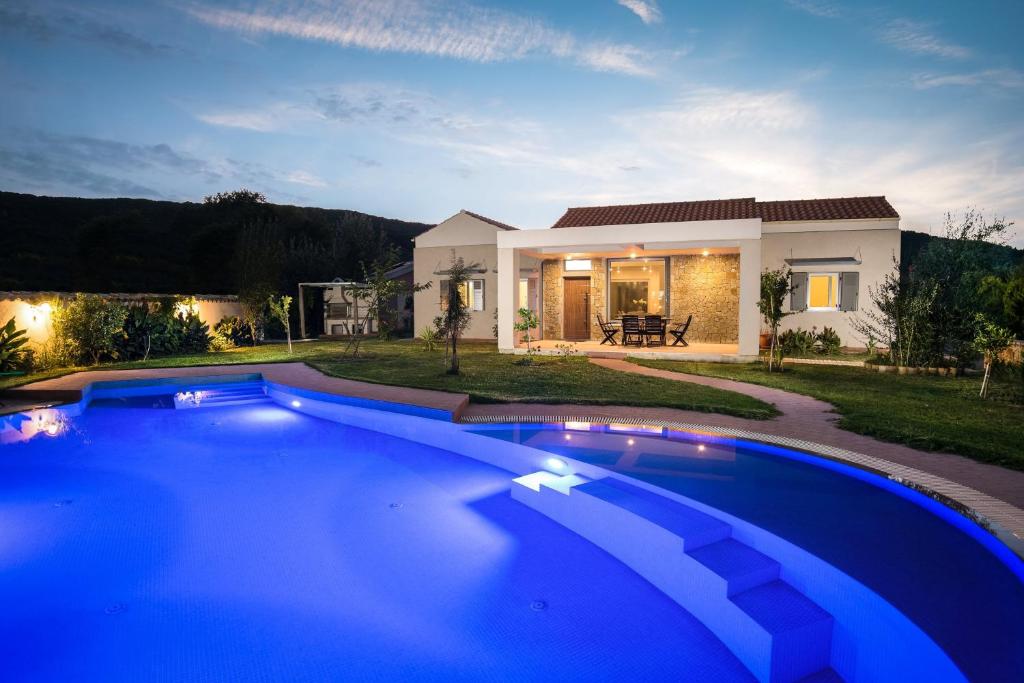 莫拉蒂卡Three Stars Luxury Villas的一座大蓝色游泳池,位于房子前