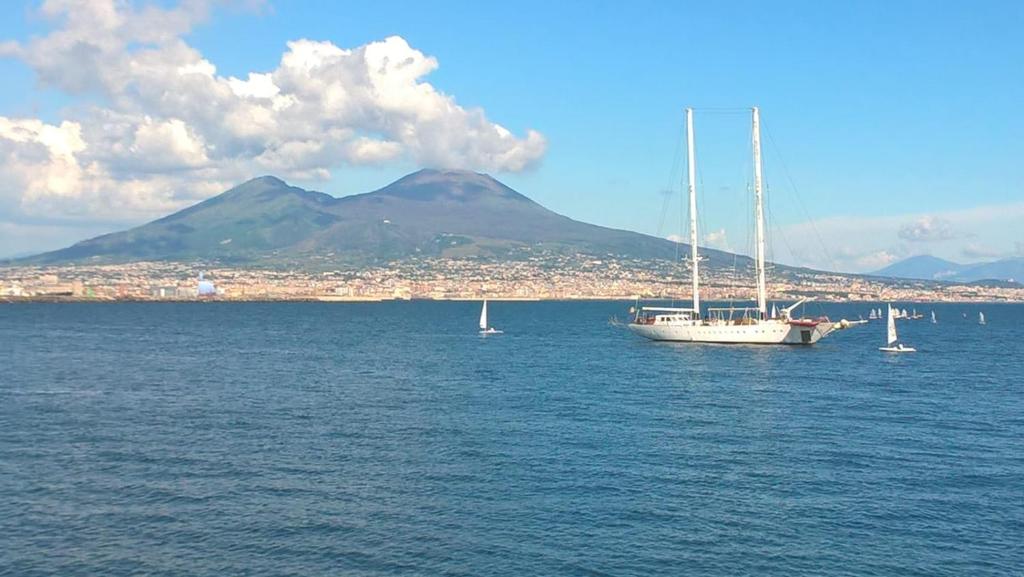 那不勒斯Napoli Storia e Mare的水中的小船,背景是山