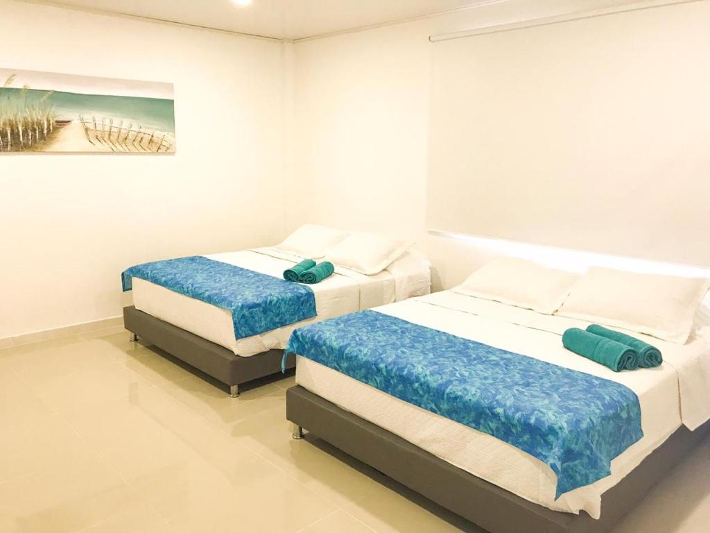 圣安德烈斯Tropical Breeze Aeropuerto的白色卧室内的两张床,配有绘画作品