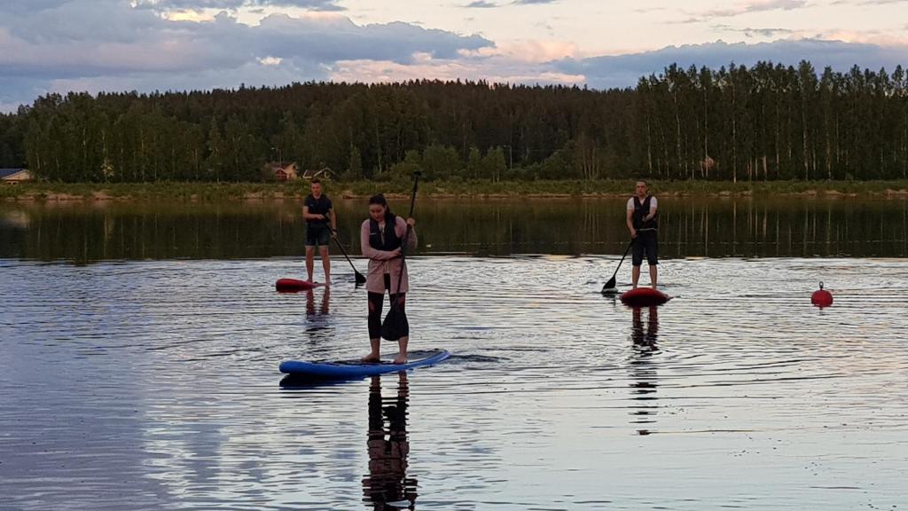 库里卡Pitkämö Canyon Camping Oy的三人站在湖上的桨板上