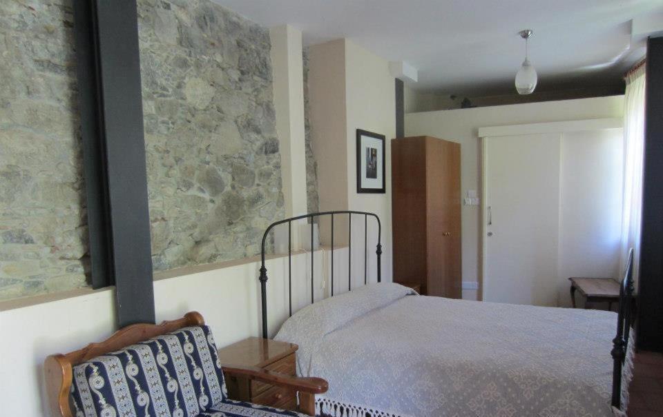 卡洛帕尼亚伊奥蒂斯圣安布罗西安德洛尼卡乡村民宿的一间卧室设有一张床和石墙