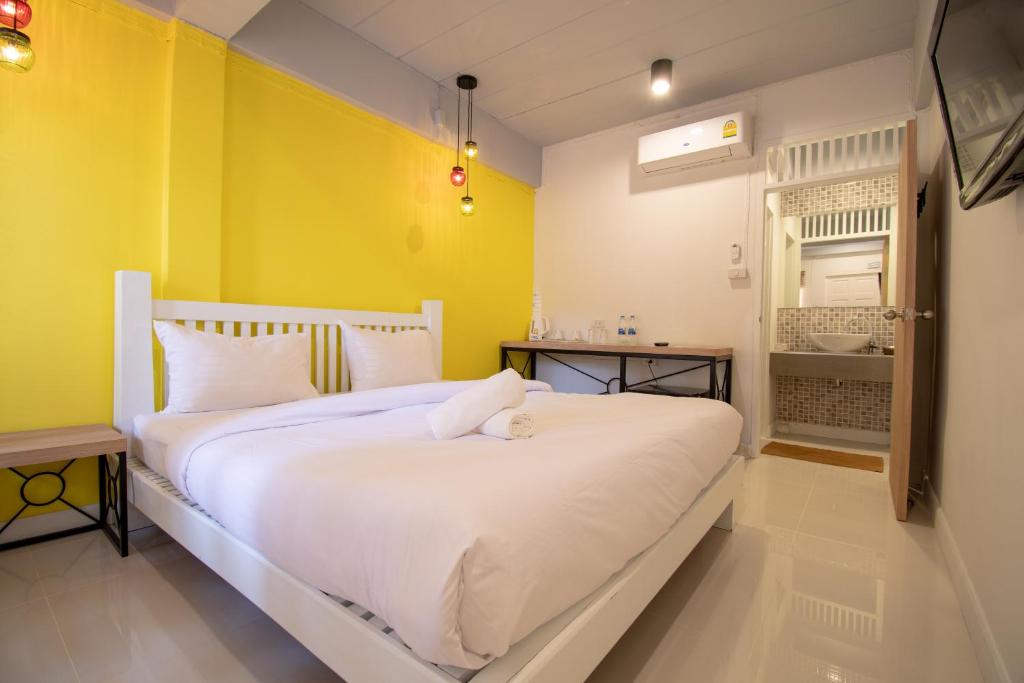 沙美岛Lazy Sandals的卧室配有白色的床和黄色的墙壁