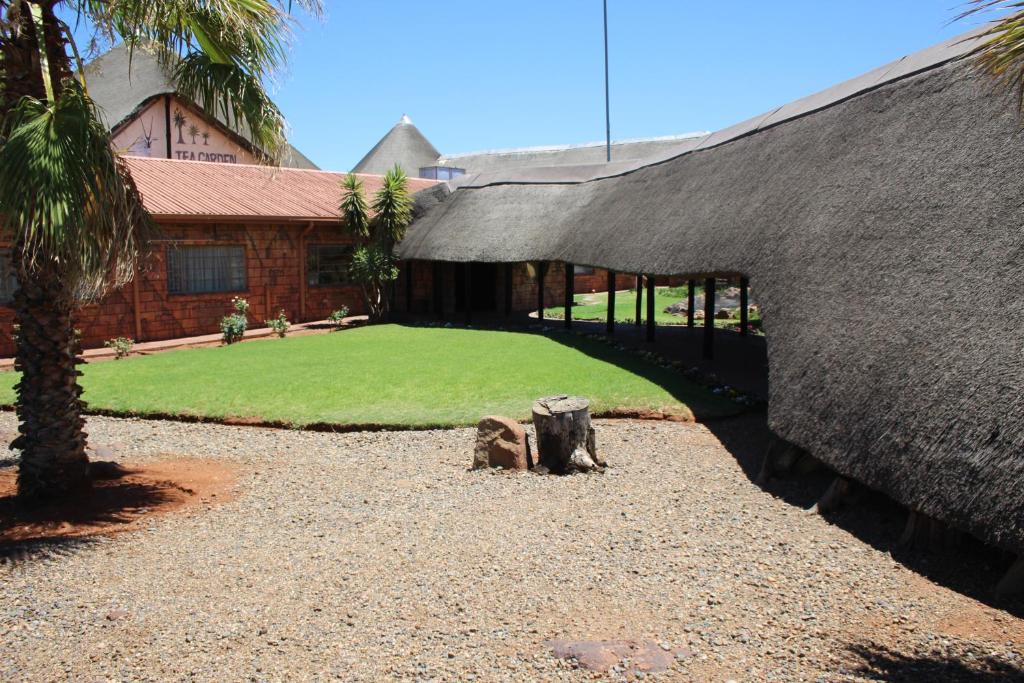 金伯利Kalahari Lodge Kimberley的一座带庭院的草屋顶建筑
