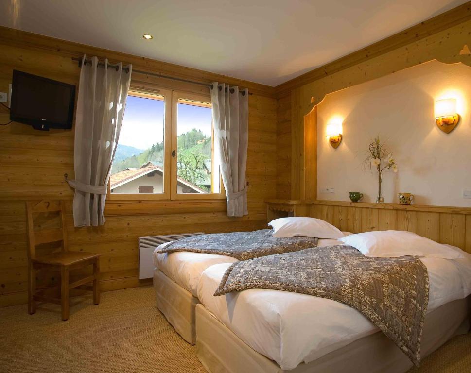 圣让德锡克斯特La ferme de sixt chambre proche La Clusaz et Grand Bornand的一间卧室设有两张床和大窗户