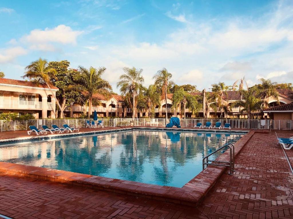 彭布罗克派恩斯大棕榈树Spa高尔夫度假酒店的一座带椅子和棕榈树的度假村游泳池