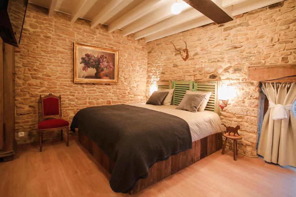 圣塞西尔Les Chambres du Chat的卧室设有一张砖墙内的大床