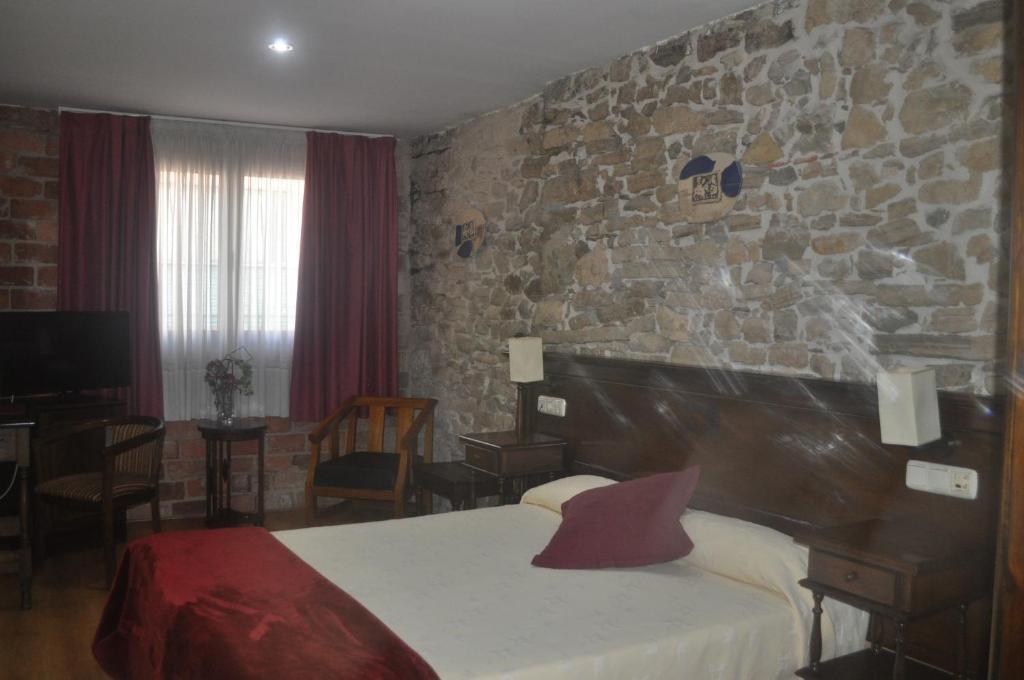 阿维莱斯敦佩德罗酒店的一间石墙卧室和一张位于客房内的床