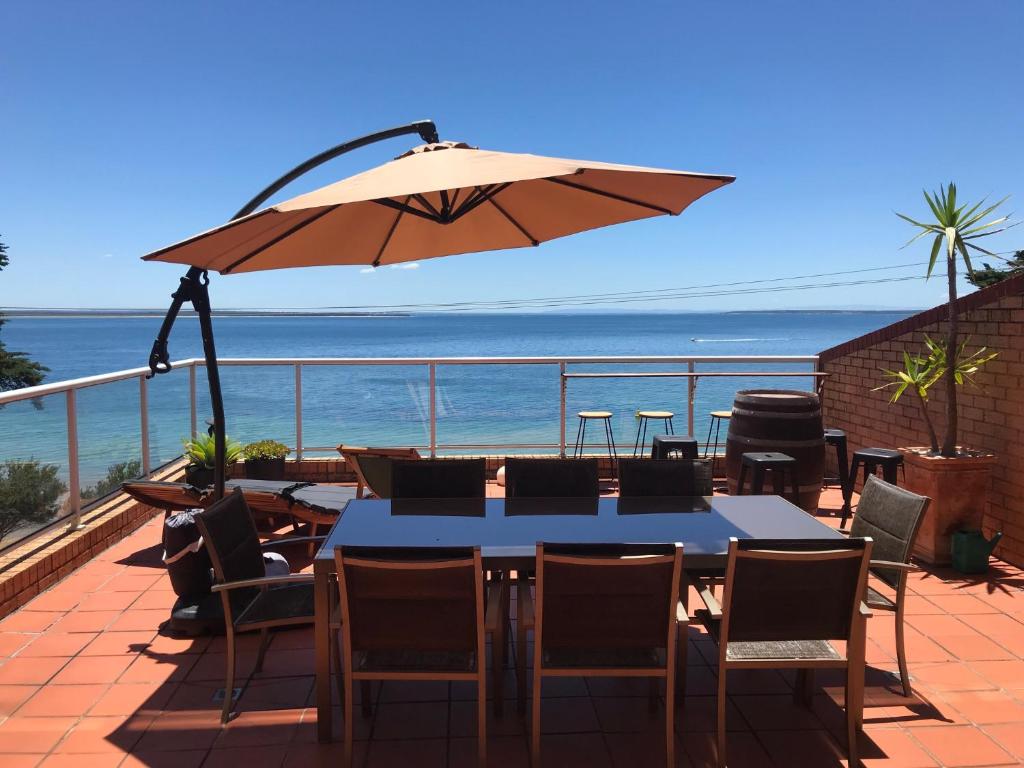 卡尔斯Cowes Beachfront Retreat的阳台配有桌椅和遮阳伞