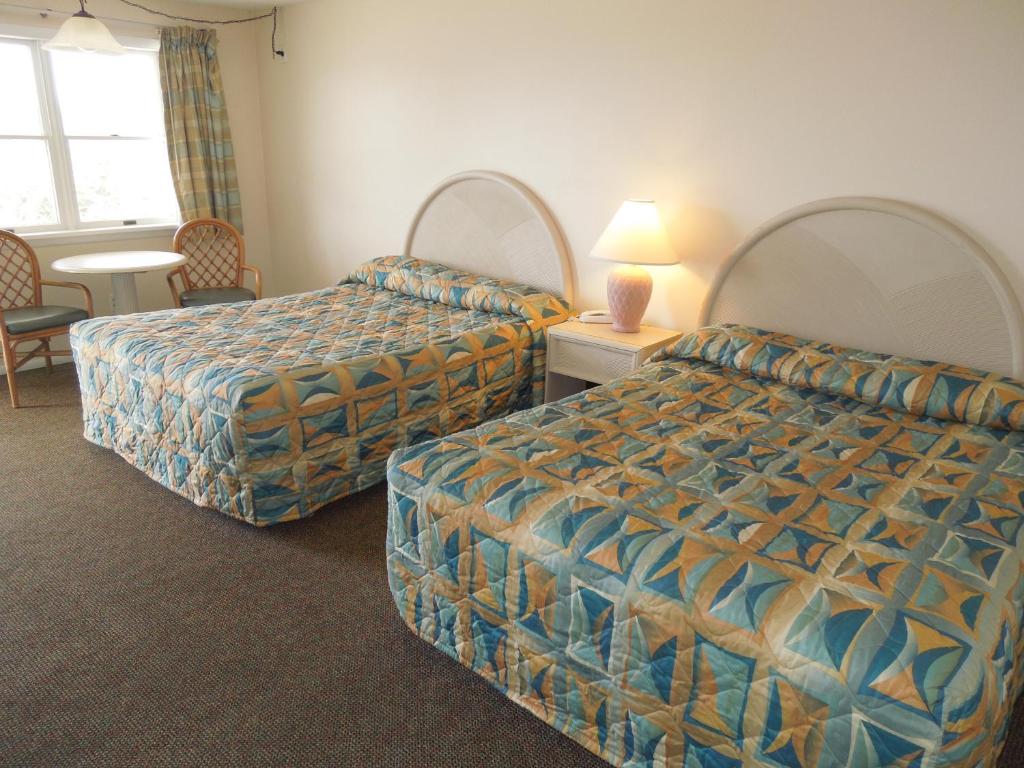五月岬郡码头汽车旅馆的酒店客房带两张床和一张桌子以及椅子。