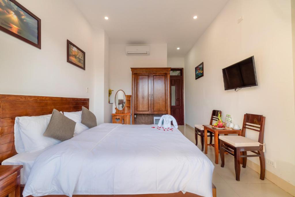 会安Hanh Nhung Villa的卧室配有一张白色大床和电视。