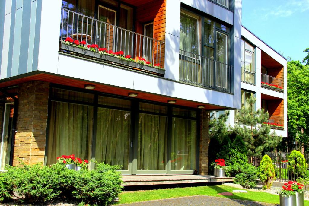 帕兰加Jūros Apartamentai的带阳台的建筑,在院子里有红色的鲜花