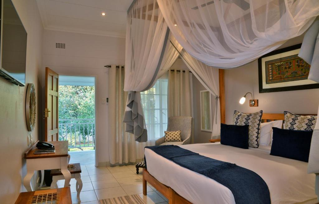 维多利亚瀑布Batonka Guest Lodge的一间卧室配有一张床、一张书桌和一个窗户。