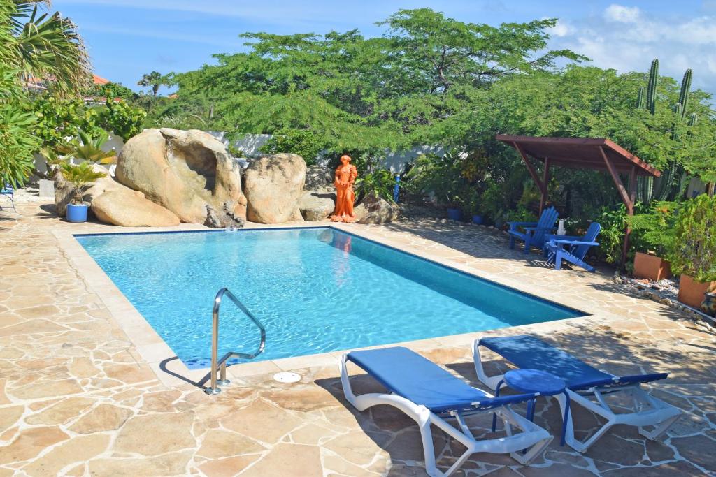 棕榈滩Villa Bougainvillea Aruba Rumba Suite的游泳池旁设有两把椅子和一个女人