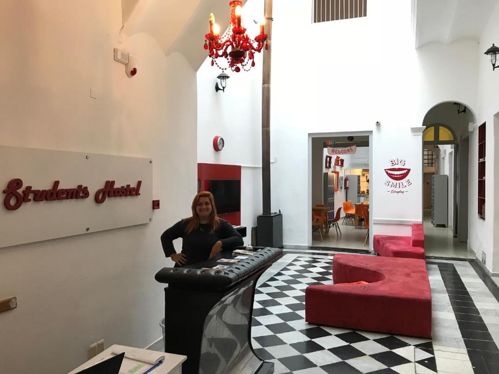 蒙得维的亚Student’s Hostel的坐在酒吧里,坐在一个红色椅子的房间里的女人