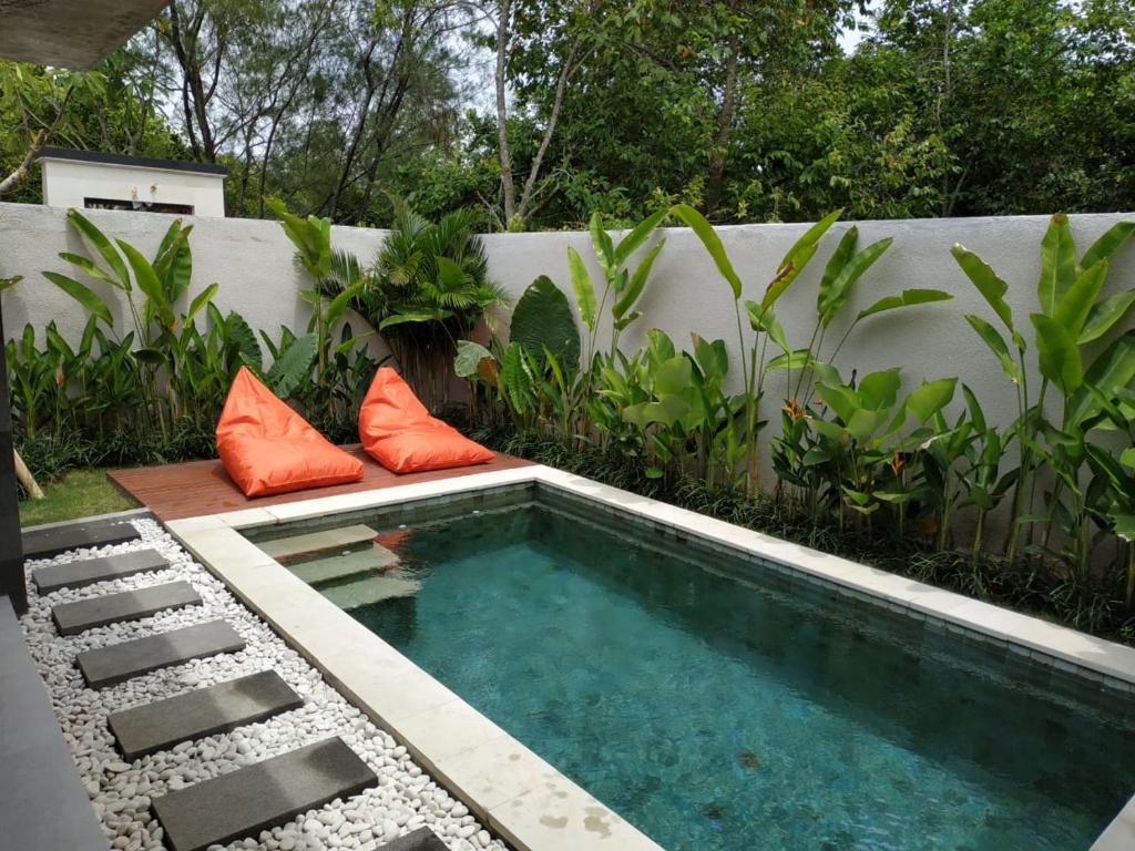 坎古La Isla Villas Bali的一个带橙色枕头的小游泳池,位于围栏旁