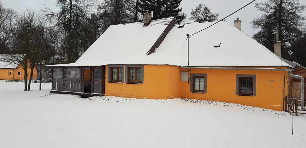 里马若夫Chata Na Kovárně的屋顶上积雪的黄色房子