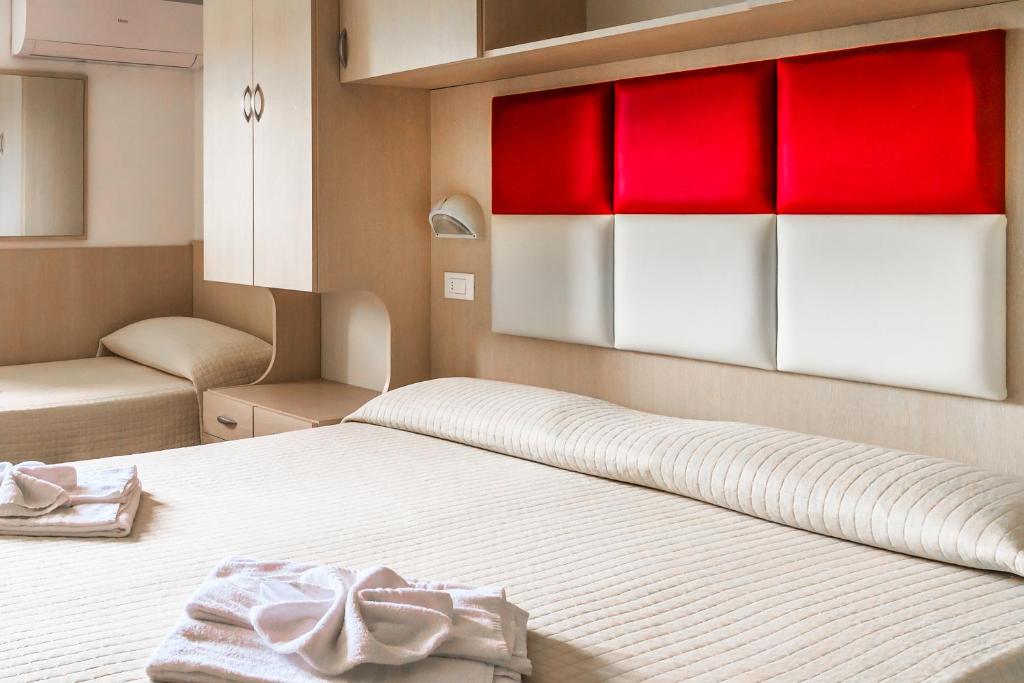 里米尼斯特雷萨酒店的一间卧室配有一张红色和白色的橱柜。