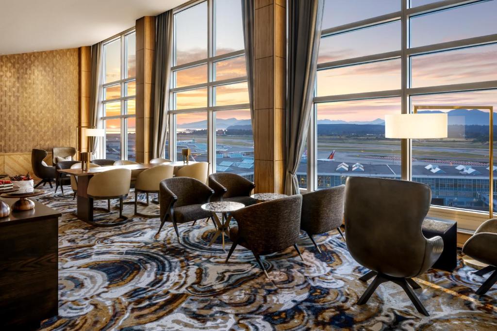 里士满Fairmont Gold at Fairmont Vancouver Airport的酒店大堂设有桌椅和大窗户。