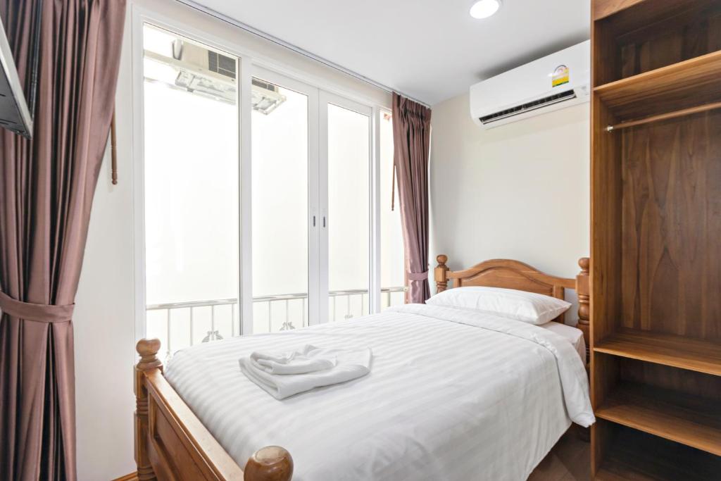 曼谷Royale 8 Ville Guest House的一间卧室配有一张带白色床单的床和一扇窗户。