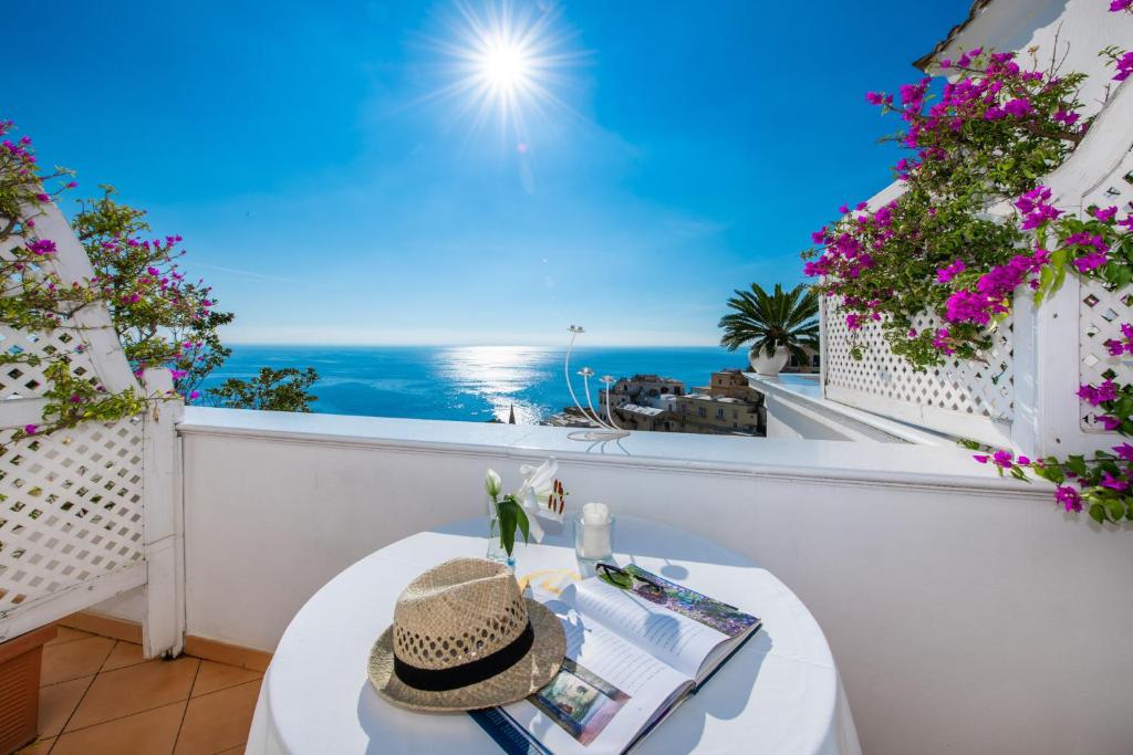 波西塔诺Villa Yiara的阳台配有带帽子的桌子,享有海景