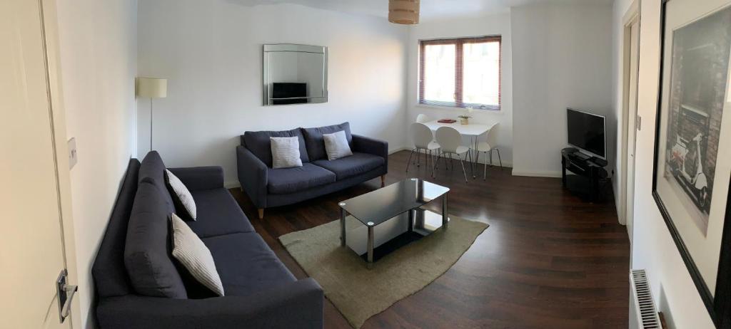 阿伯丁布卢姆菲尔德 - 阿伯丁服务式公寓的客厅配有蓝色的沙发和桌子
