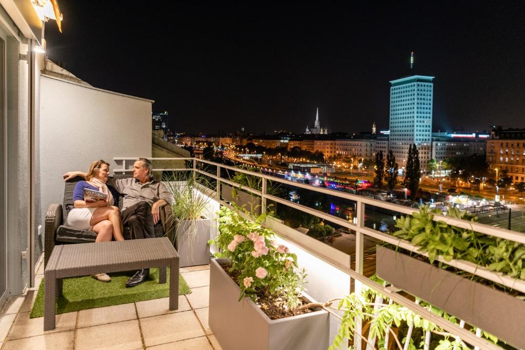 维也纳Skyflats Vienna Ring View的男人和女人在晚上坐在阳台上