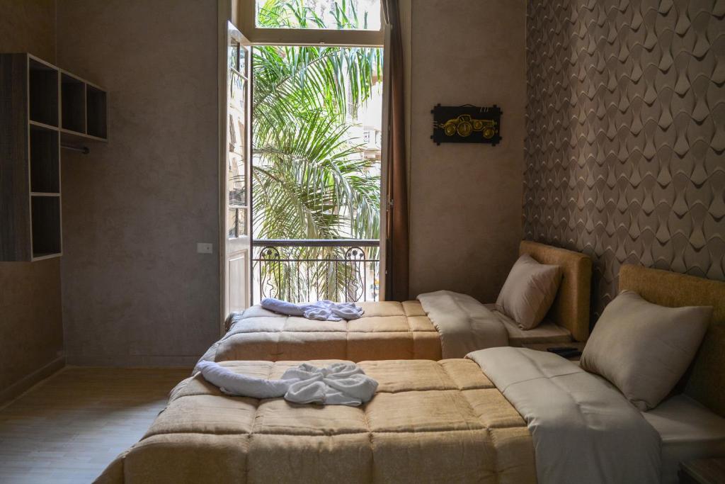 开罗Holy Sheet Hostel的带大窗户的客房内的三张床