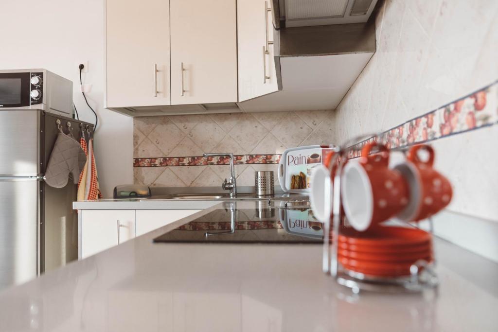 塞博河畔卡莱塔Apartamento Cuesta del salado的厨房配有白色橱柜和柜台上的红杯