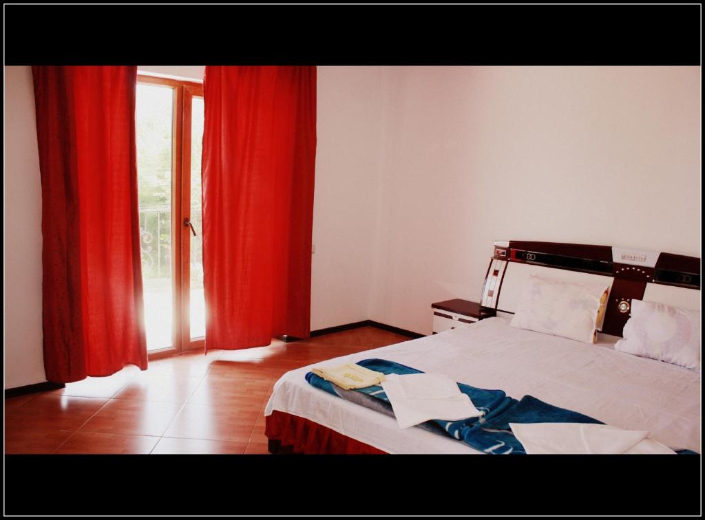 南埃福列西尔维娅别墅旅馆的一间卧室配有一张带红色窗帘的床和一扇窗户