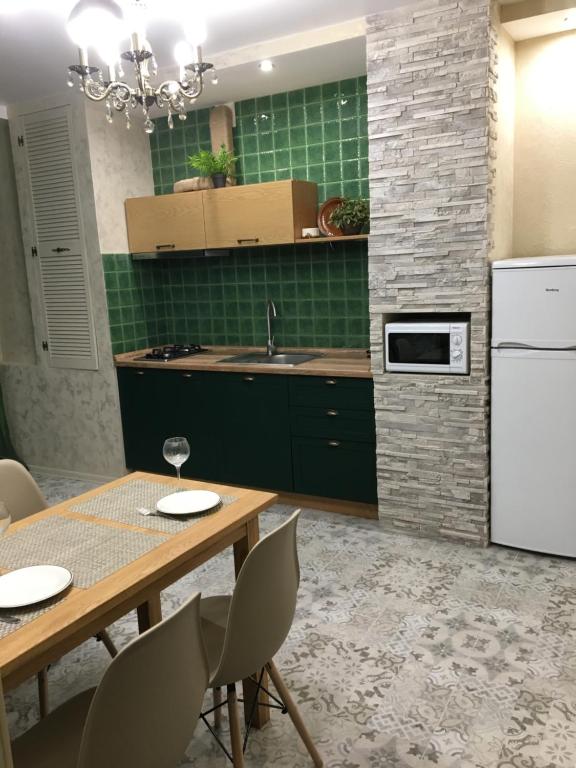 Petropavlovskaya BorshchagovkaСофиевский квартал的厨房配有木桌和白色冰箱。